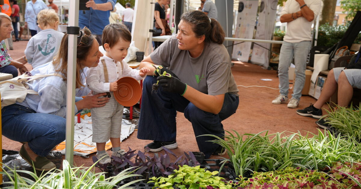 Un agent des Espaces Verts expliquent à un jeune garçon les plantes.