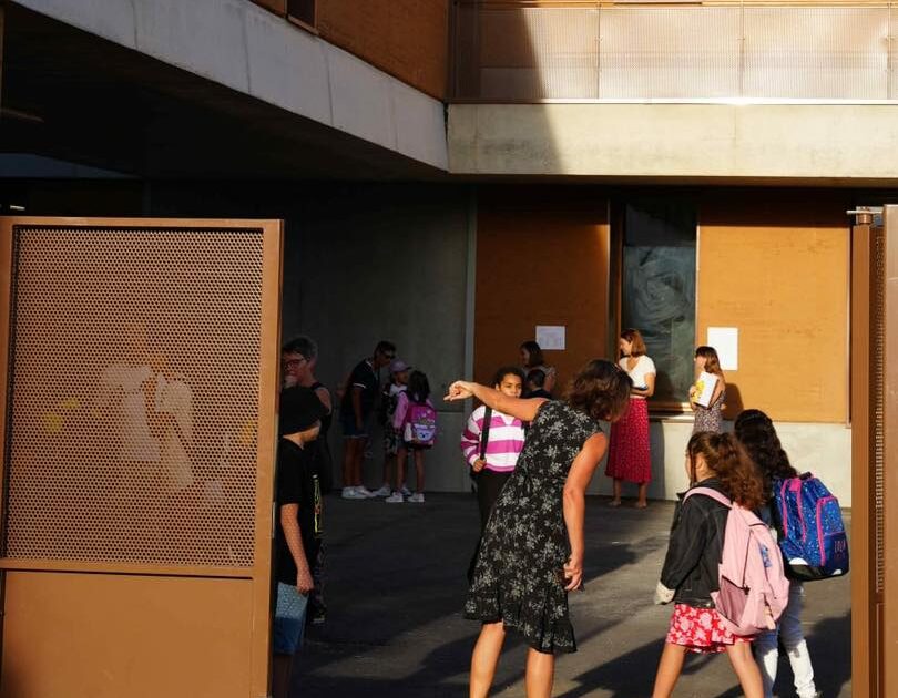 Photo d'enfants arrivant à l'école avec un professeur pour les accueillir