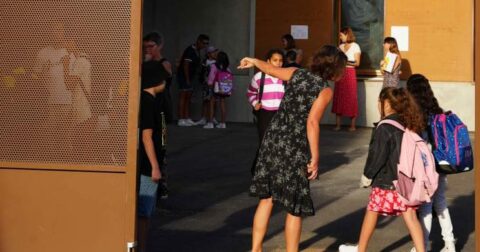 Photo d'enfants arrivant à l'école avec un professeur pour les accueillir