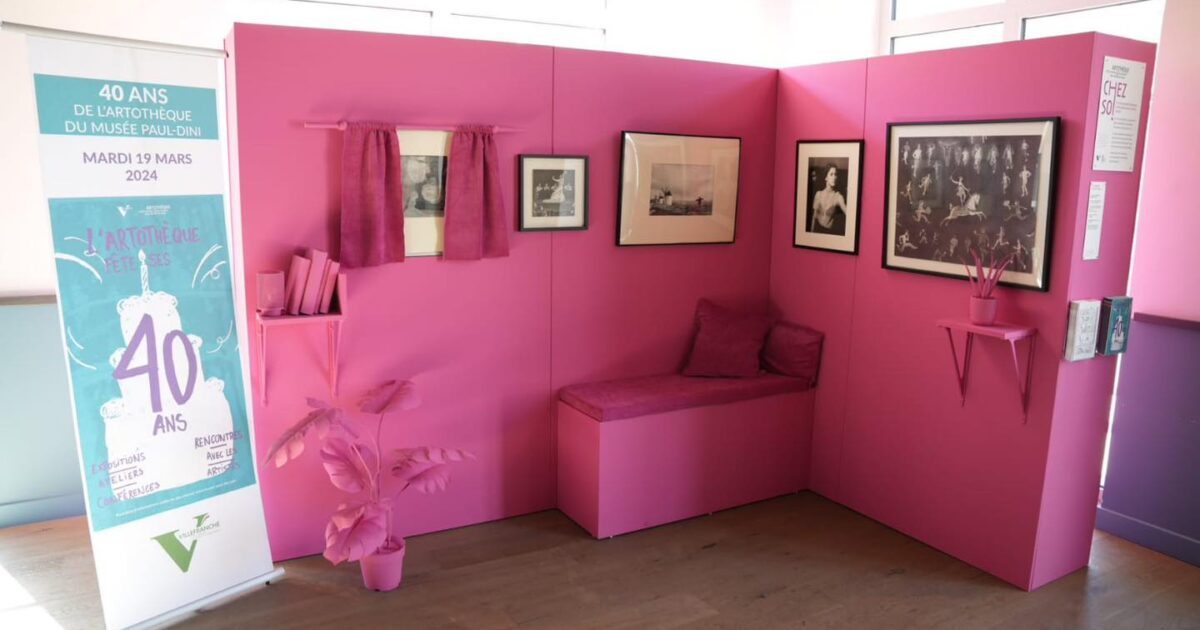 Photo structure itinérante de l'artothèque montrant deux murs rose formant un coin détente avec tableaux, plantes et banquette de repos