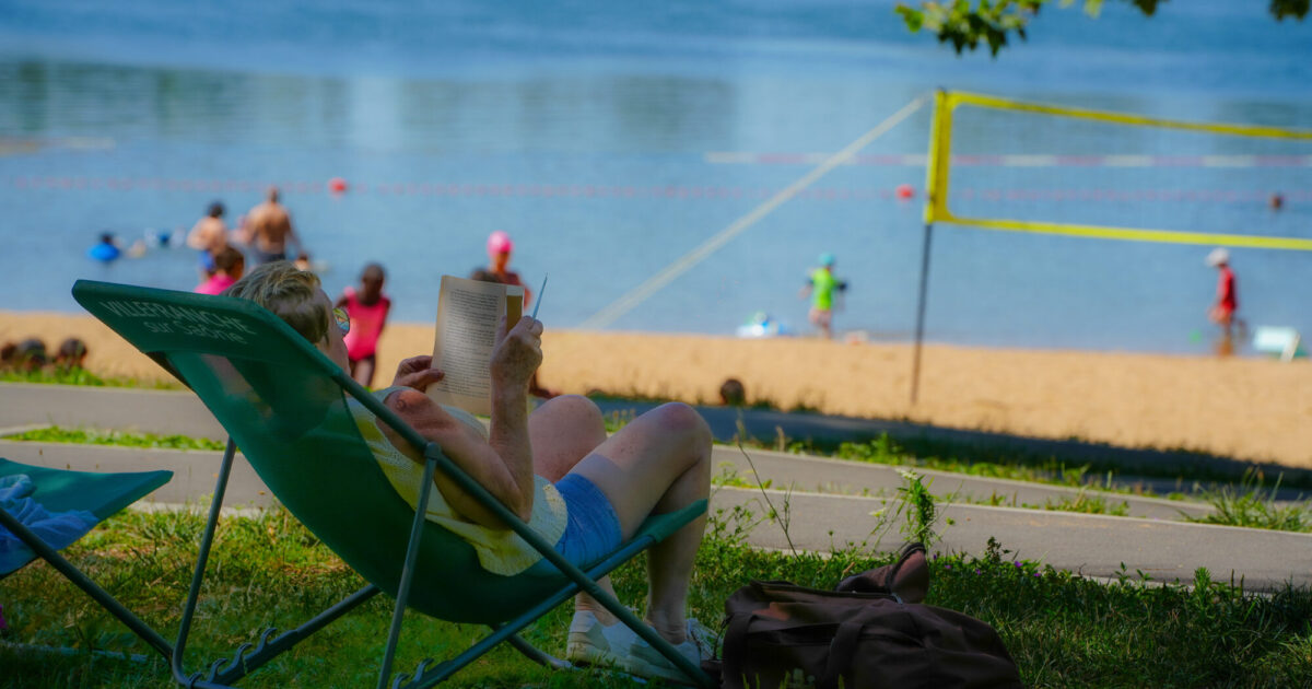 Une personne lit un livre sur un transat au plan d'eau de Bordelan