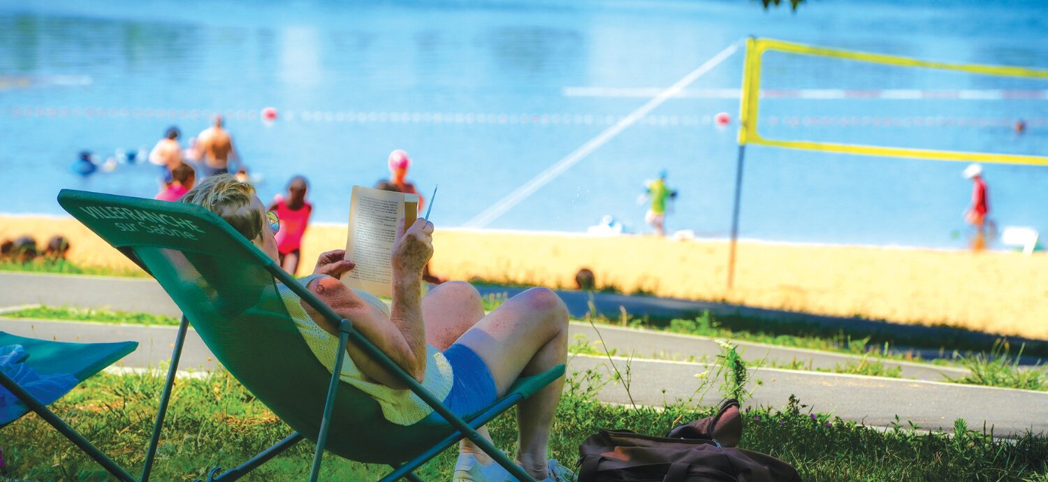 Photo du Plan d'eau du Bordelan. Une dame se prélassent sur une chilienne avec un livre