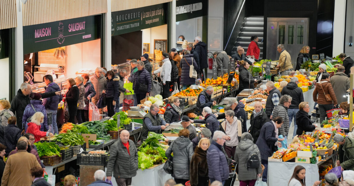 Photo du Marché Couvert de Villefranche, rénové, avec les étals colorés, des forains et des usagers faisant leur marché