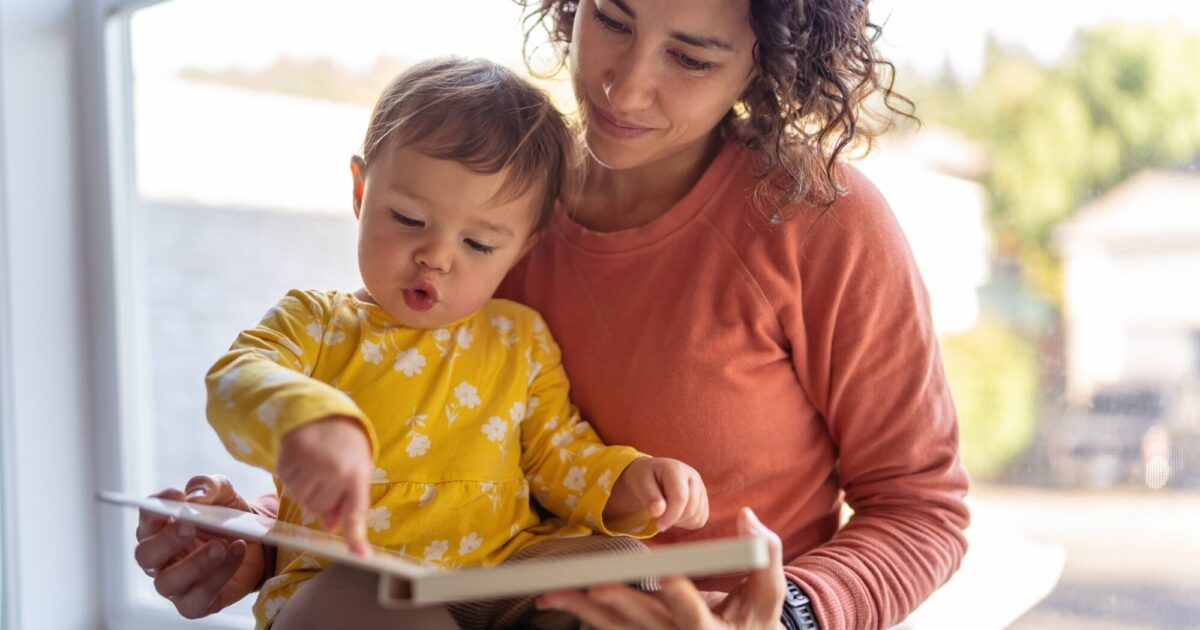 une assistante maternelle lit un livre avec un jeune enfant.